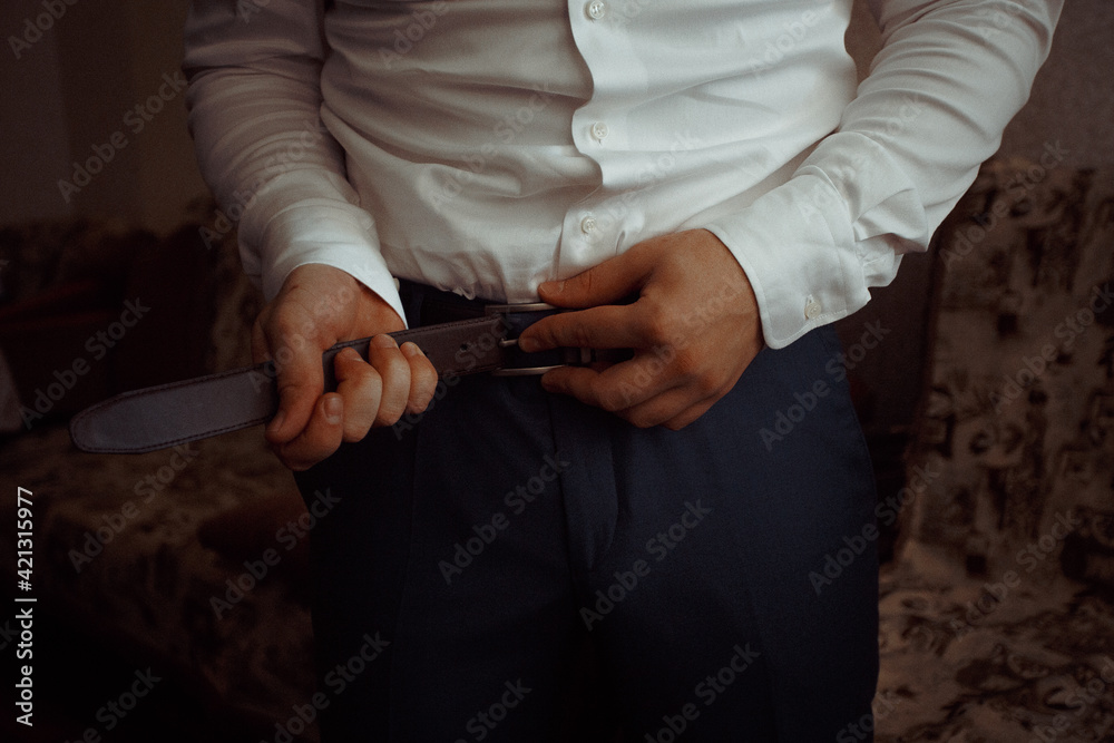 business man in shirt dresses and straightens leather belt close-up