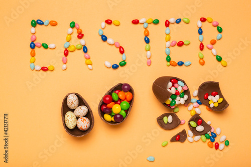 Colorful eggs with the word Easter wrote with sweet candies, free space for greeting text. Chocolate eggs as a symbol of Easter