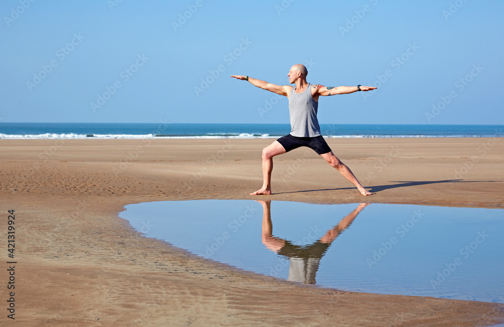Man (40-44 years old) performing 'warrior pose' on deserted beach in Woolacombe, North Devon Man (40-44 years old) performing 'warrior pose' on deserted beach in Woolacombe, North Devon