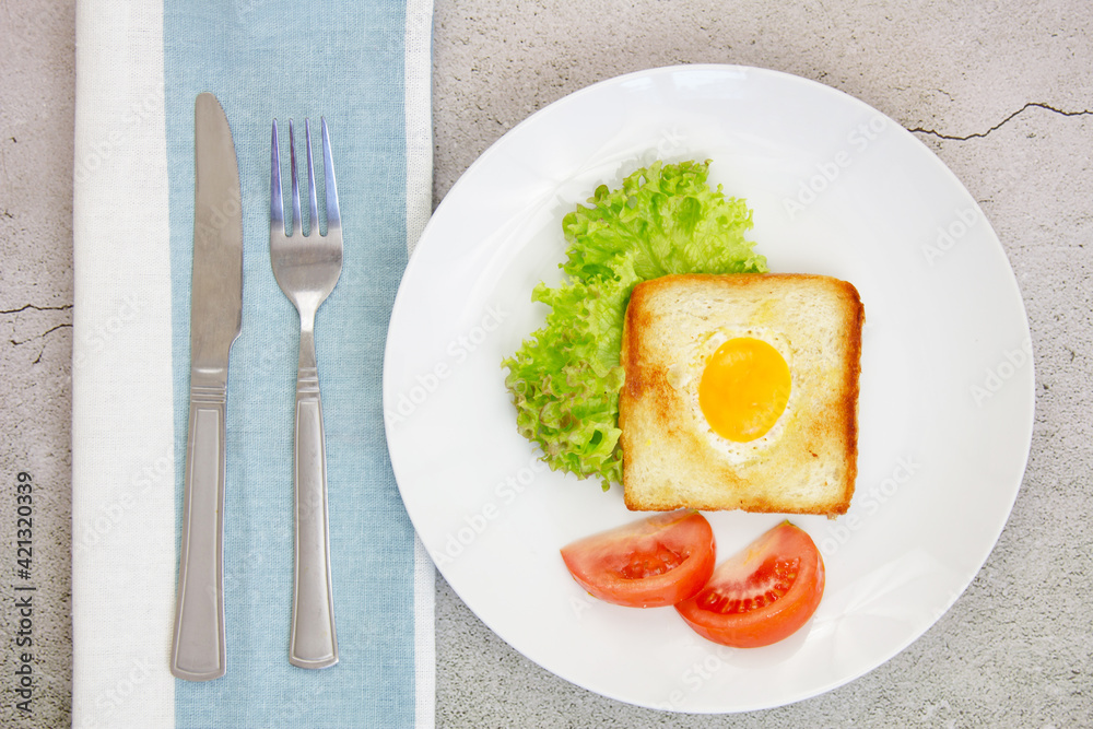 Scrambled eggs in toast with green lettuce and tomatoes on a gray plate on a gray stone background with a towel and utensils. Scrambled eggs in toast with green lettuce and tomatoes on a gray plate on a gray stone background with a towel and utensils.