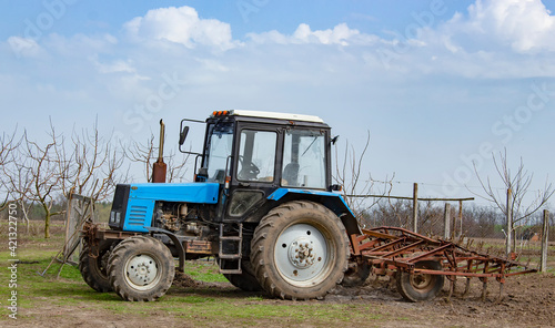 Blue tractor with a cultivator in the garden