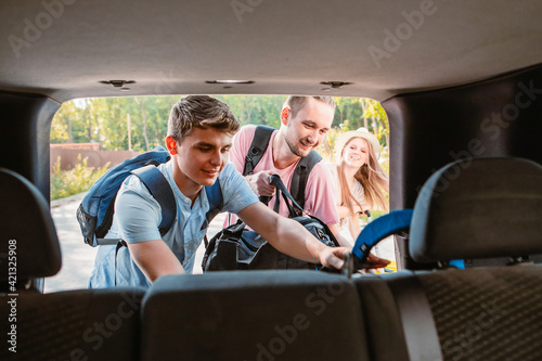 friends load car trunk with baggage