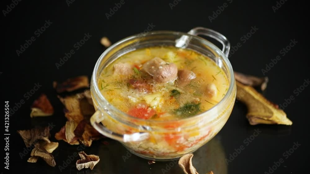 vegetarian vegetable soup with porcini mushrooms in a glass bowl isolated on black background vegetarian vegetable soup with porcini mushrooms in a glass bowl isolated on black background