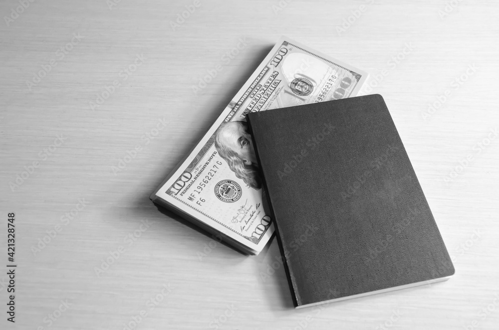 Passport and stack of dollar bills lie on the table. Money and document. Travel concept. Cash money for freedom of movement. Passport and stack of dollar bills lie on the table. Money and document. Travel concept. Cash money for freedom of movement.