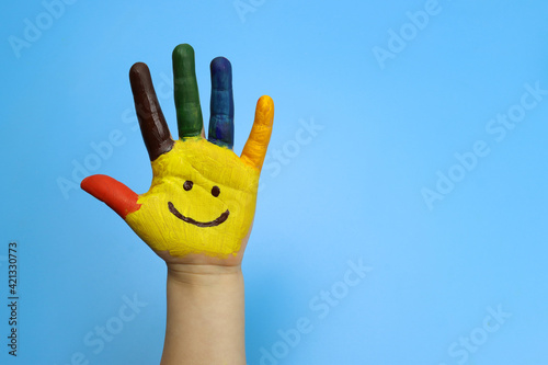 Child hand painted in colorful paint on a blue background