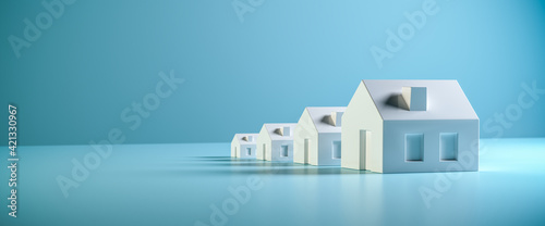 Which size of house can you afford? Concept shot: four differently sized models of houses on a blue background. Copy space available, web banner format photo
