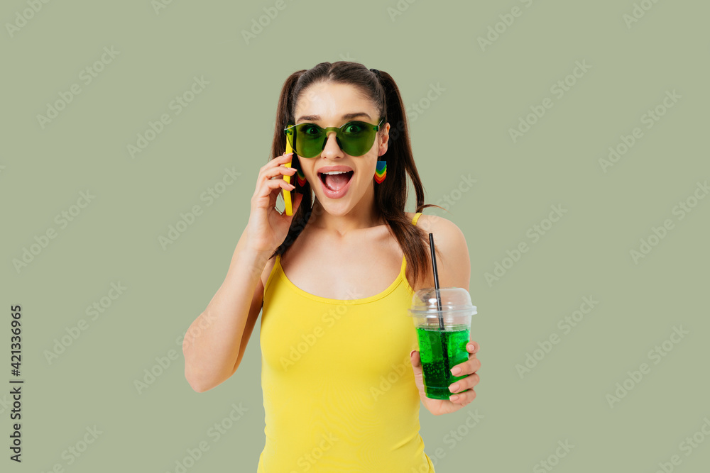 Excited young woman wearing summer outfit and colored sunglasses smiling Excited young woman wearing summer outfit and colored sunglasses smiling