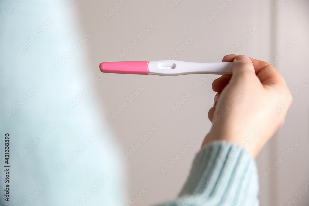 Young woman holding negative pregnancy test,home pregnancy test showing negative result close up Young woman holding negative pregnancy test,home pregnancy test showing negative result close up