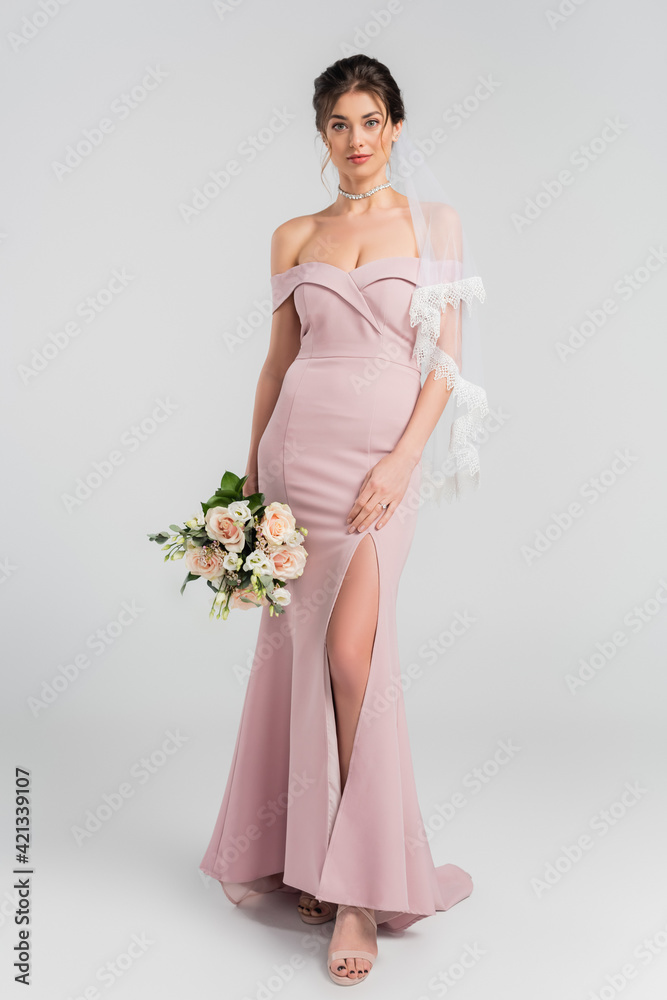 full length view of elegant bride posing with wedding bouquet on grey full length view of elegant bride posing with wedding bouquet on grey