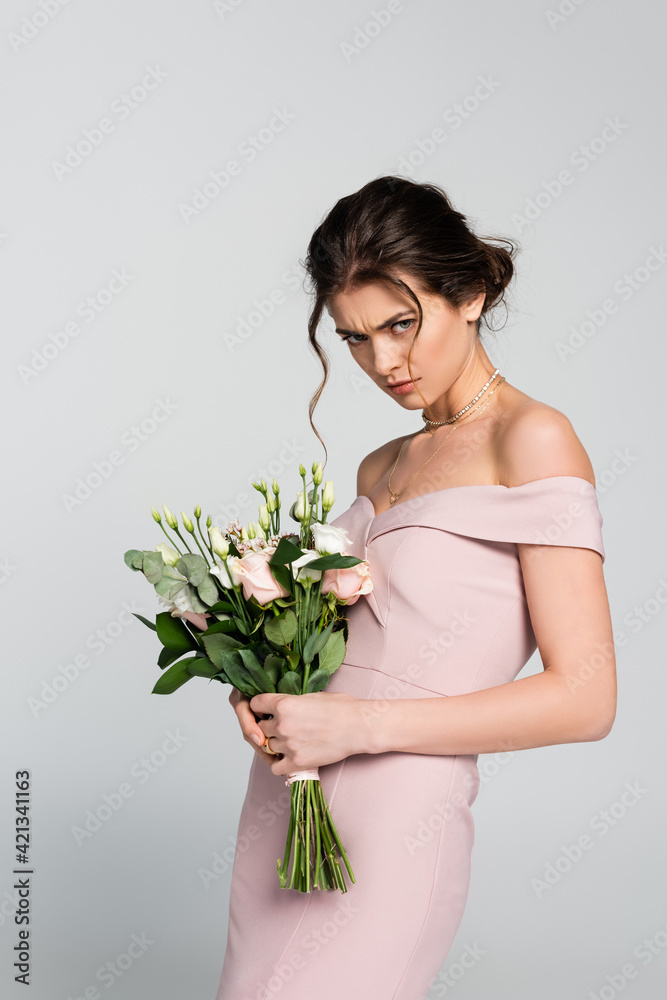 angry fiancee looking at camera while holding wedding bouquet isolated on grey angry fiancee looking at camera while holding wedding bouquet isolated on grey