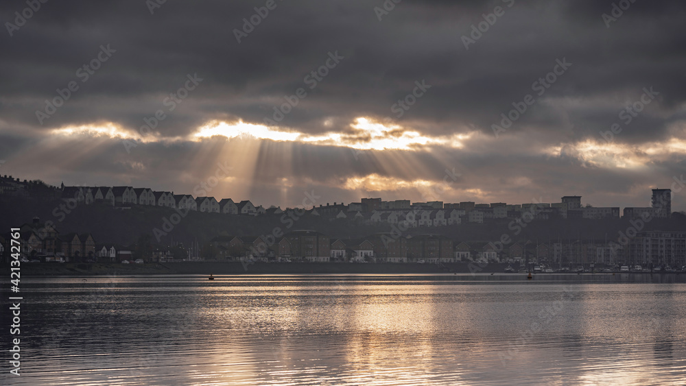Sun beams bursting through the clouds, over Penarth Marina, on the edge of Cardiff Bay, Wales