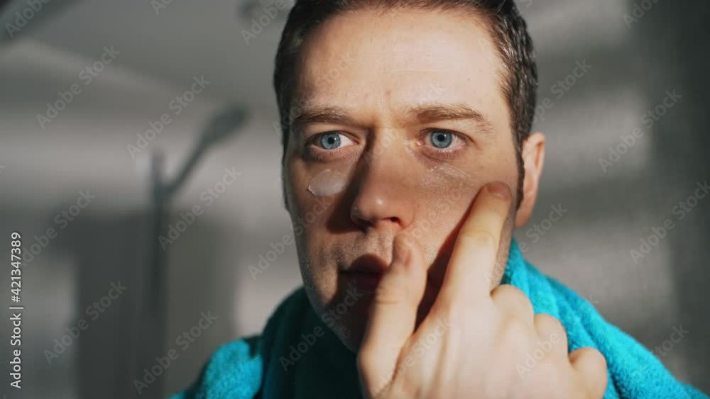Man applying cream on face in bathroom. Man applying cream on face in bathroom.