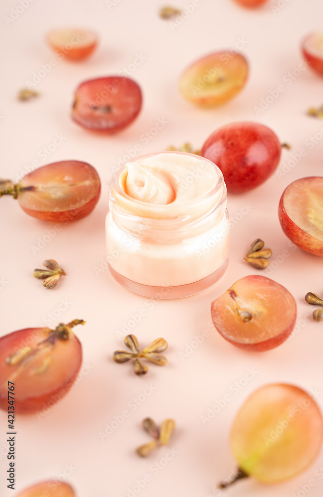 Concept organic extract nature grape seeds oil in cream for skin care in home. Creative modern flat lay composition with fresh red grapes and seeds in pink background. Naturecore. Eco. Close up.