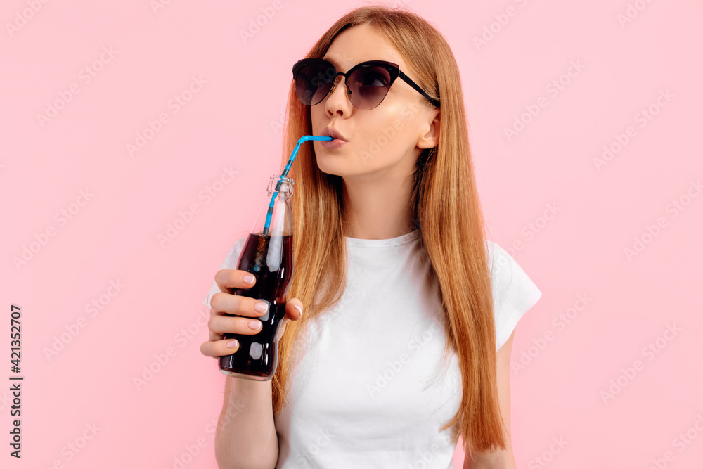young woman in sunglasses drinking a refreshing drink on a pink background young woman in sunglasses drinking a refreshing drink on a pink background