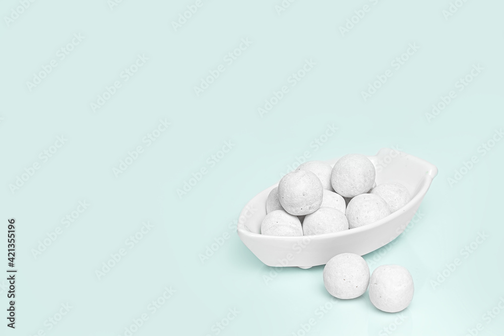 White round candies in a white ceramic vase. Blue background. Place for your text. High quality photo