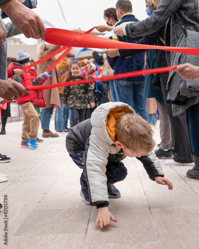 Children walk under ribbon and enjoy at the street