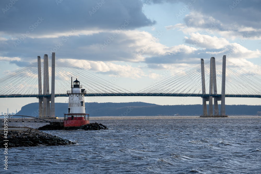 Tarrytown, NY - USA - Mar. 14, 2021: Landscape view of the Tarrytown Light, a sparkplug lighthouse on the east side of the Hudson River. The Mario M. Cuomo Bridge in the distance.
