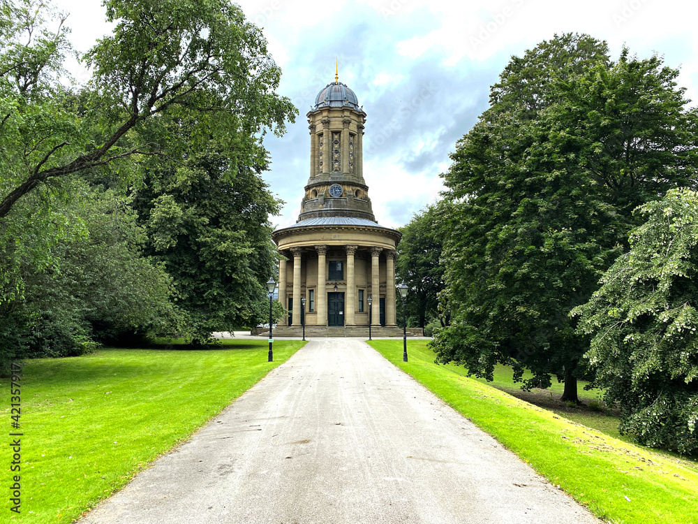 View of the, Victorian church in the village of Saltaire, with a small road, trees, and green lawns in the foreground.
