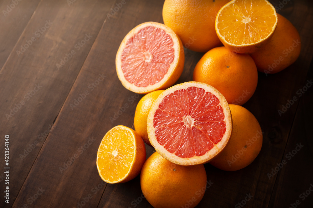 half cut ripe orange and grapefruit and several whole oranges on brown rustic wooden table with copy space half cut ripe orange and grapefruit and several whole oranges on brown rustic wooden table with copy space