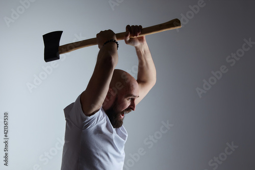 man of Caucasian appearance emotionally swings an axe. photo shoot in the studio