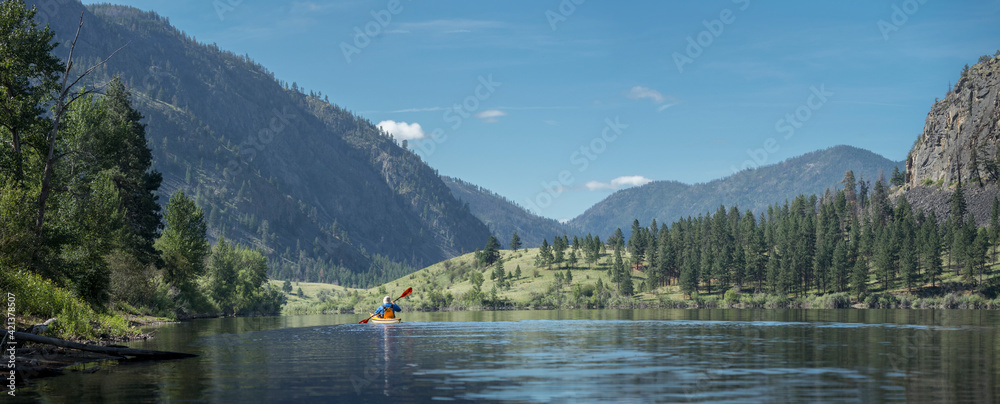USA, Washington State. A male kayaker paddles a kayak on a Blue Lake in the Sinlahekin Wildlife Area. Okanagan County.