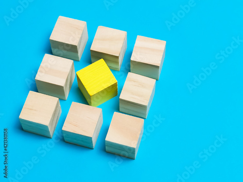 Diversity  individuality or difference concept. Selective focus wooden cubes with yellow color at the center isolated on blue background.