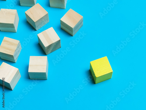 Dissenting opinion, stand out and different concepts. Selective focus wooden cubes with one yellow color isolated on blue background.