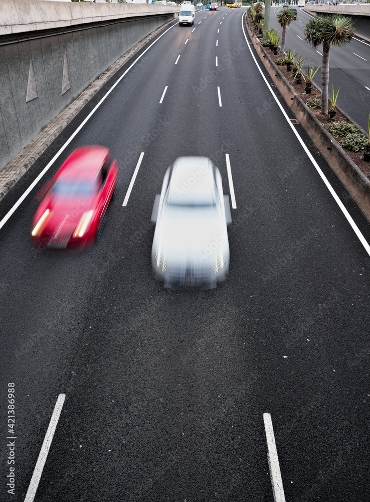 Two cars approaching in movement on a black asplalt road, light trails and intentional movement/zoom effect. Two cars approaching in movement on a black asplalt road, light trails and intentional movement/zoom effect.