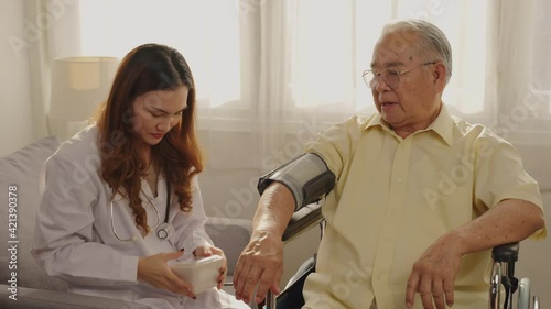 Asian doctor cardiologist wearing uniform checking older man blood pressure with tonometer during visit, checkup, Thai young female nurse holding medical electronic device, healthcare and treatment.