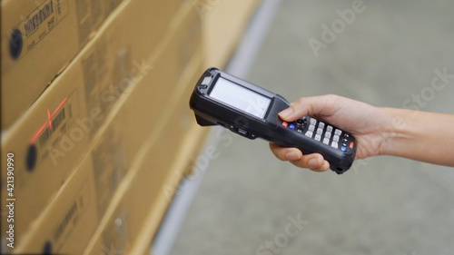 Close up hand scanning products with barcode scanner in warehouse.