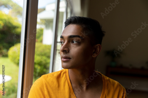 Mixed race man looking through a window and thinking