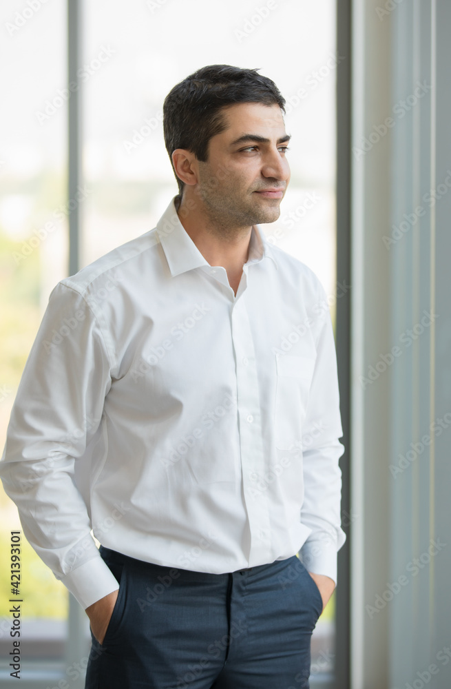 Portrait vertical with concept of Happiness Business Man look confident and happy wearing white shirt standing look outside windows with hands in pockets shoot indoor with morning light Portrait vertical with concept of Happiness Business Man look confident and happy wearing white shirt standing look outside windows with hands in pockets shoot indoor with morning light