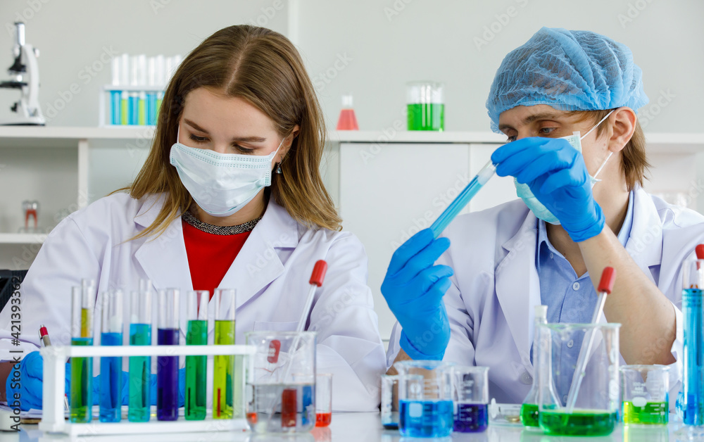 Caucasian man and woman scientist are discussing about testing results. Man hold test tube and science equipment microscope, many test tube put on table in laboratory Caucasian man and woman scientist are discussing about testing results. Man hold test tube and science equipment microscope, many test tube put on table in laboratory