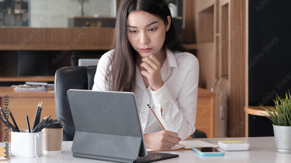 Fototapeta premium Photo of cheerful joyful asian woman writing down notes holding tablet for data analysis