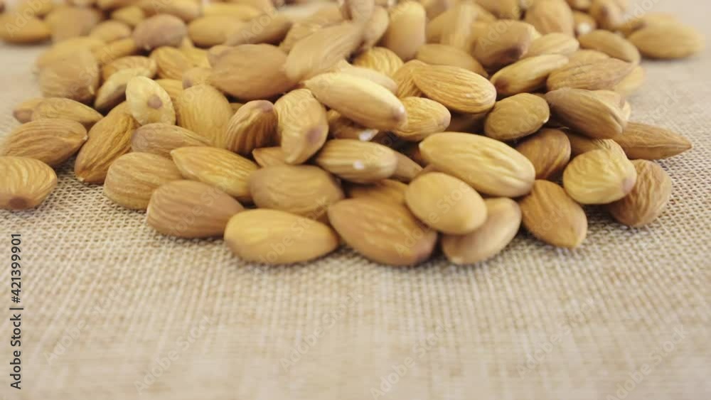 Close up almonds seed rotate on brown fabric, Slow motion almond kernels rotation with brick background, Throwing almond nuts rotation, Concept whole grains of food for healthy. Close up almonds seed rotate on brown fabric, Slow motion almond kernels rotation with brick background, Throwing almond nuts rotation, Concept whole grains of food for healthy.