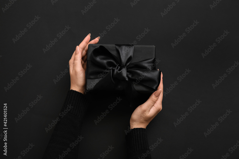 Female hands with gift box on dark background Female hands with gift box on dark background