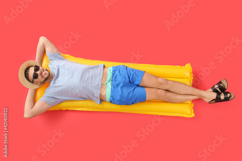 Εκτύπωση καμβά Handsome man lying on inflatable mattress against color background