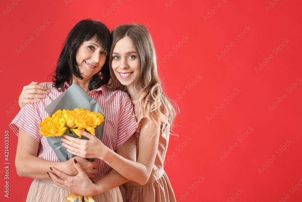 Adult daughter and her mother with bouquet of flowers on color background Adult daughter and her mother with bouquet of flowers on color background