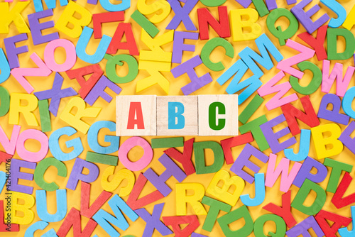 Alphabet on wooden tiles and ABC on a cube against yellow background. Concept of child leraning education development