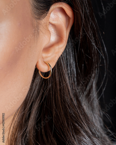 Fototapeta Close-up macro portrait of a woman wearing gold earring