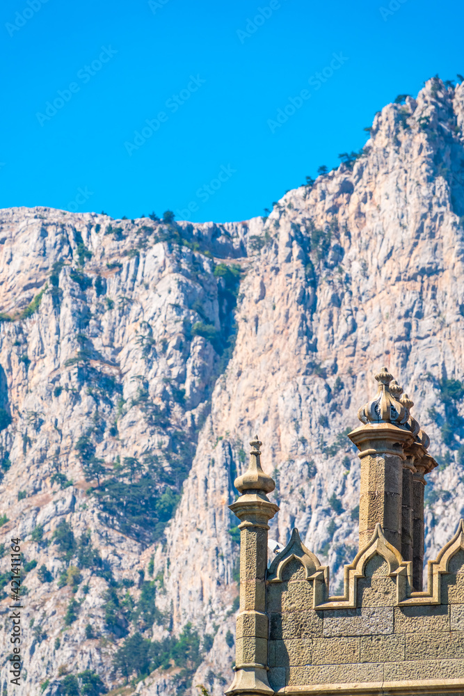 The walls and towers of the old palace on the background of high mountains and blue sky