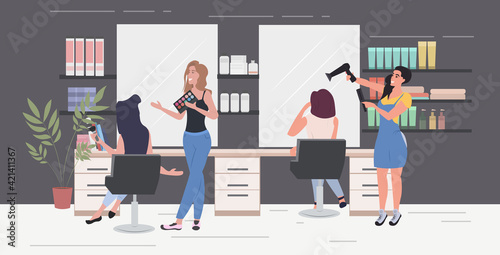 hairdresser using hair dryer making hair style to her client women testing eyeshadow palette beauty salon interior horizontal full length