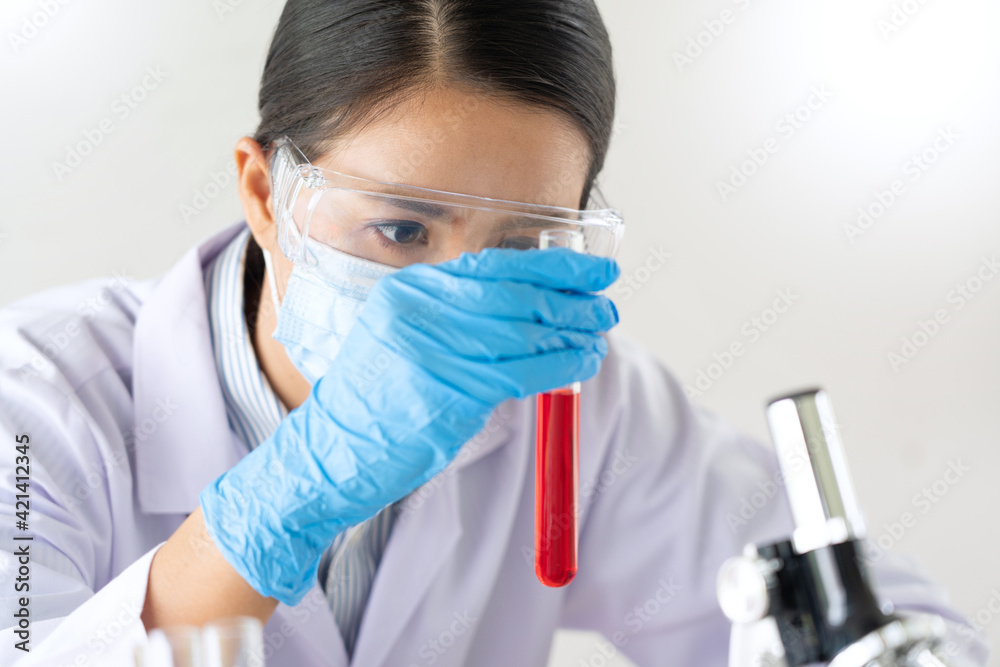 Young Asian scientist Working looking through a microscope doing research for analyzing a Experiments sample in a forensic laboratory. Young Asian scientist Working looking through a microscope doing research for analyzing a Experiments sample in a forensic laboratory.