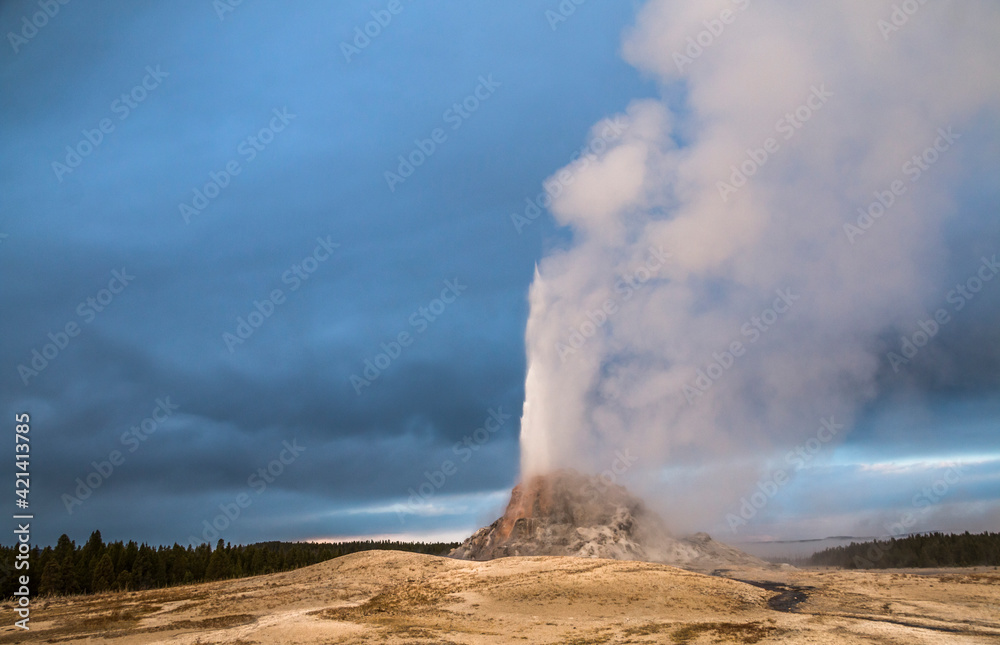 dramatic photo of an erupting geyser in Yellowstone national  park in wyoming.