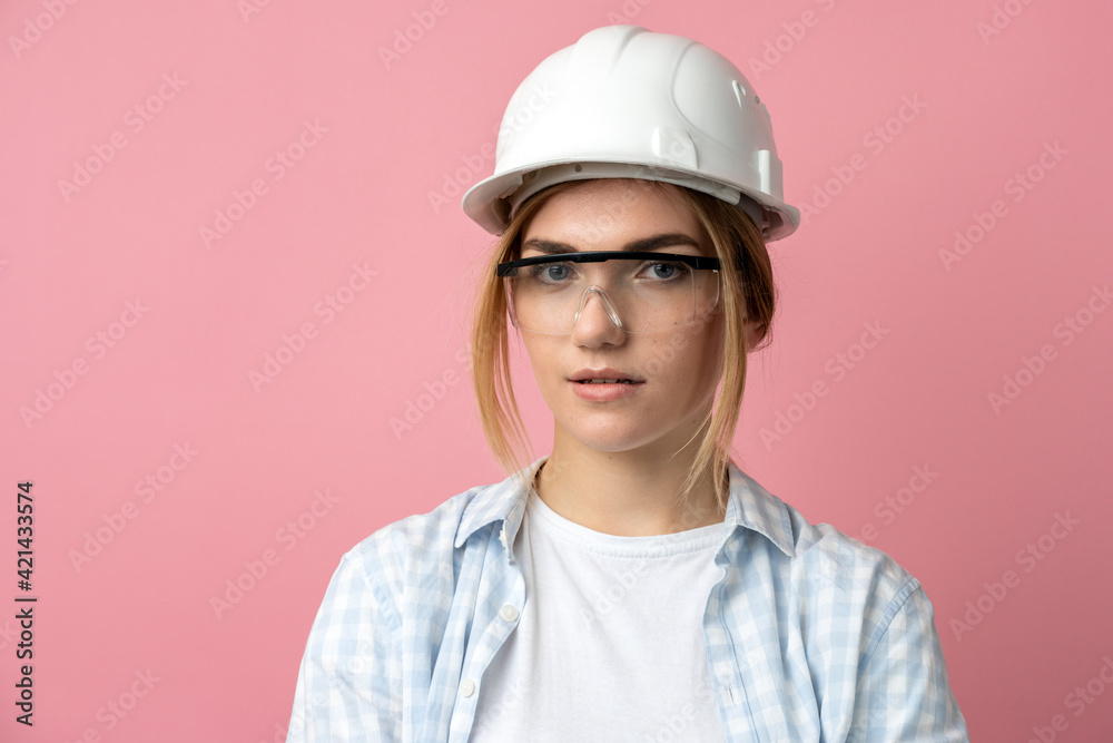 Young girl in a construction helmet on a background of a pink wall. Beautiful girl in construction glasses and helmet isolated on a pink wall. Young girl in a construction helmet on a background of a pink wall. Beautiful girl in construction glasses and helmet isolated on a pink wall.