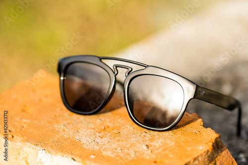 Sunglasses with black lenses and black frame shoot outside in a sunny day closeup . Selective focus. High quality photo