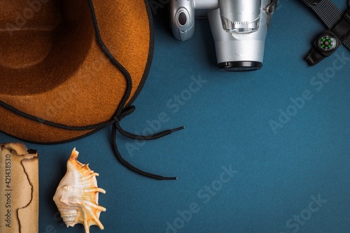 Cowboy hat, camera, compass, old paper scroll and seashell on a blue background. Travel concept