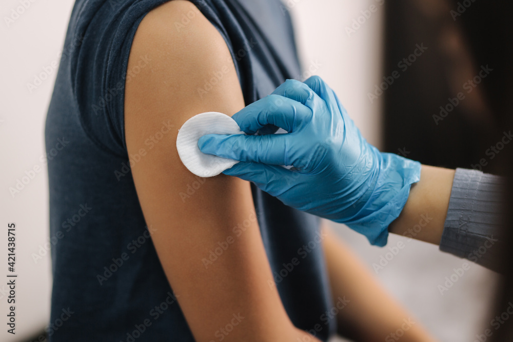 Close up of doctor using cotton before make injection to patient in medical mask. Covid-19 or coronavirus vaccine for boy
