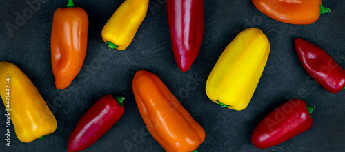 Colorful mini peppers on black background, banner