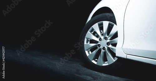 Alloy wheels of the white car are turning on the cement road of parking lot with copy space on the left photo